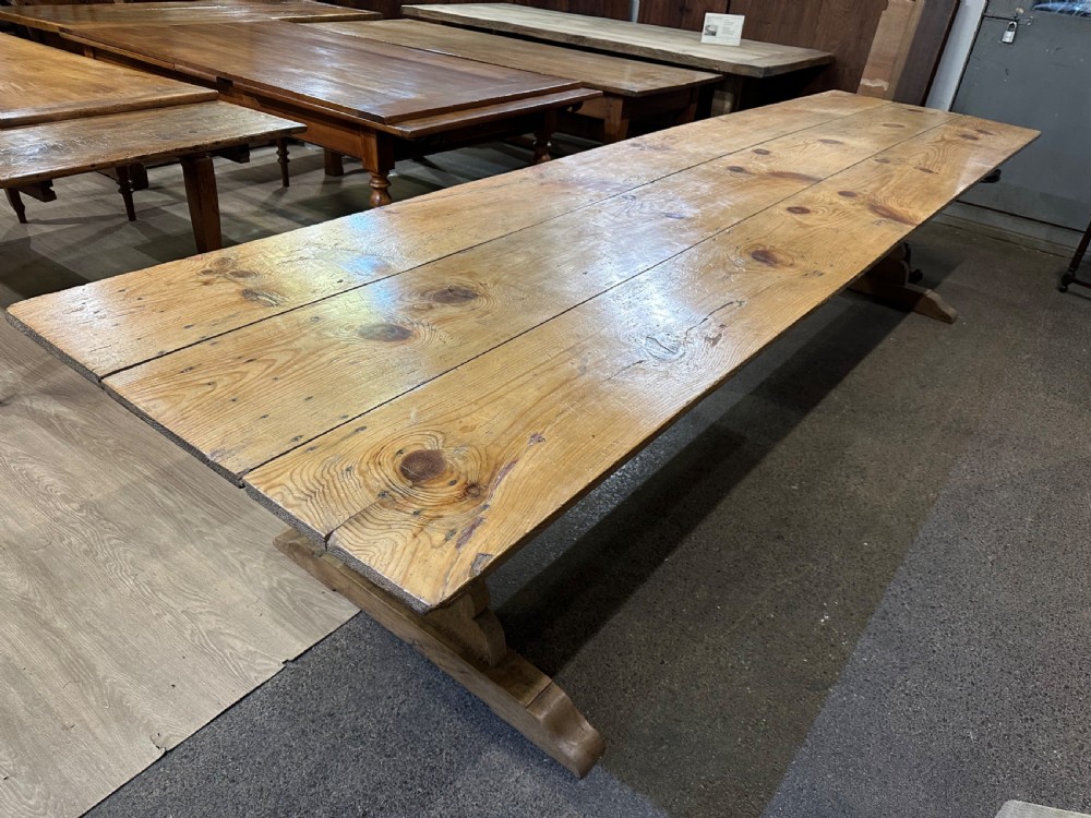 A long rectangular pine trestle dining table with a multi-plank top and a central timber stretcher base. View IV