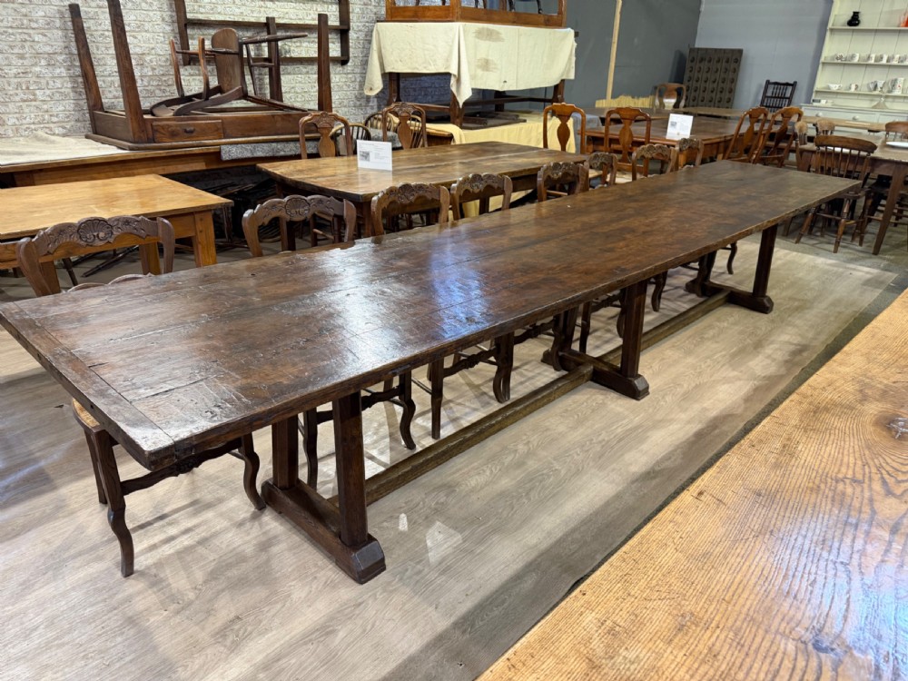An exceptionally long 18th-century dark oak dining table featuring a solid plank top resting on a sturdy trestle base with a central stretcher rail.