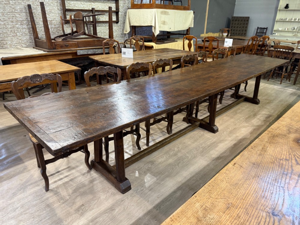 An exceptionally long 18th-century dark oak dining table featuring a solid plank top resting on a sturdy trestle base with a central stretcher rail. View II