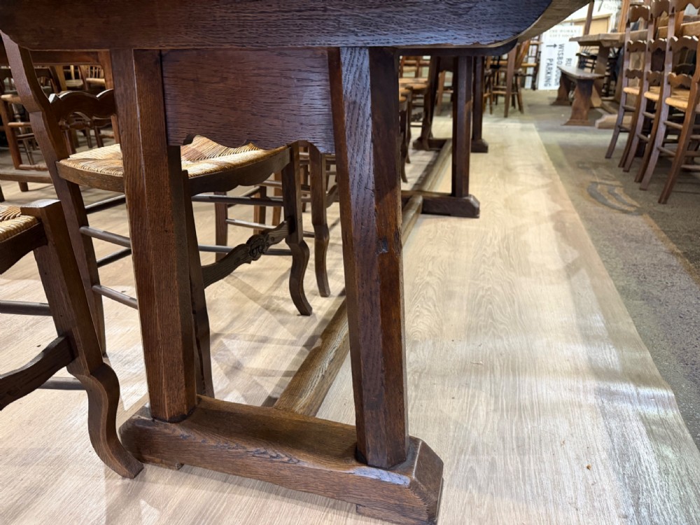 An exceptionally long 18th-century dark oak dining table featuring a solid plank top resting on a sturdy trestle base with a central stretcher rail. View III