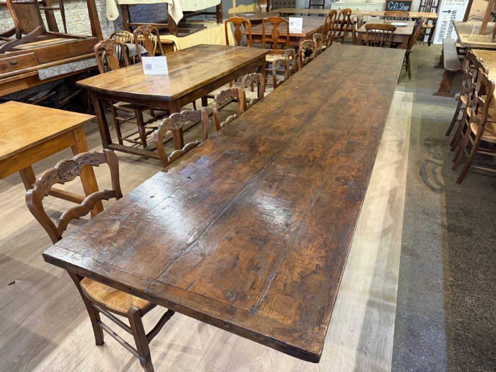 An exceptionally long 18th-century dark oak dining table featuring a solid plank top resting on a sturdy trestle base with a central stretcher rail. View IV