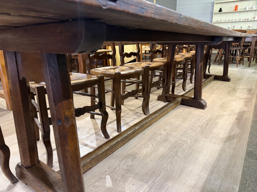 An exceptionally long 18th-century dark oak dining table featuring a solid plank top resting on a sturdy trestle base with a central stretcher rail. View V