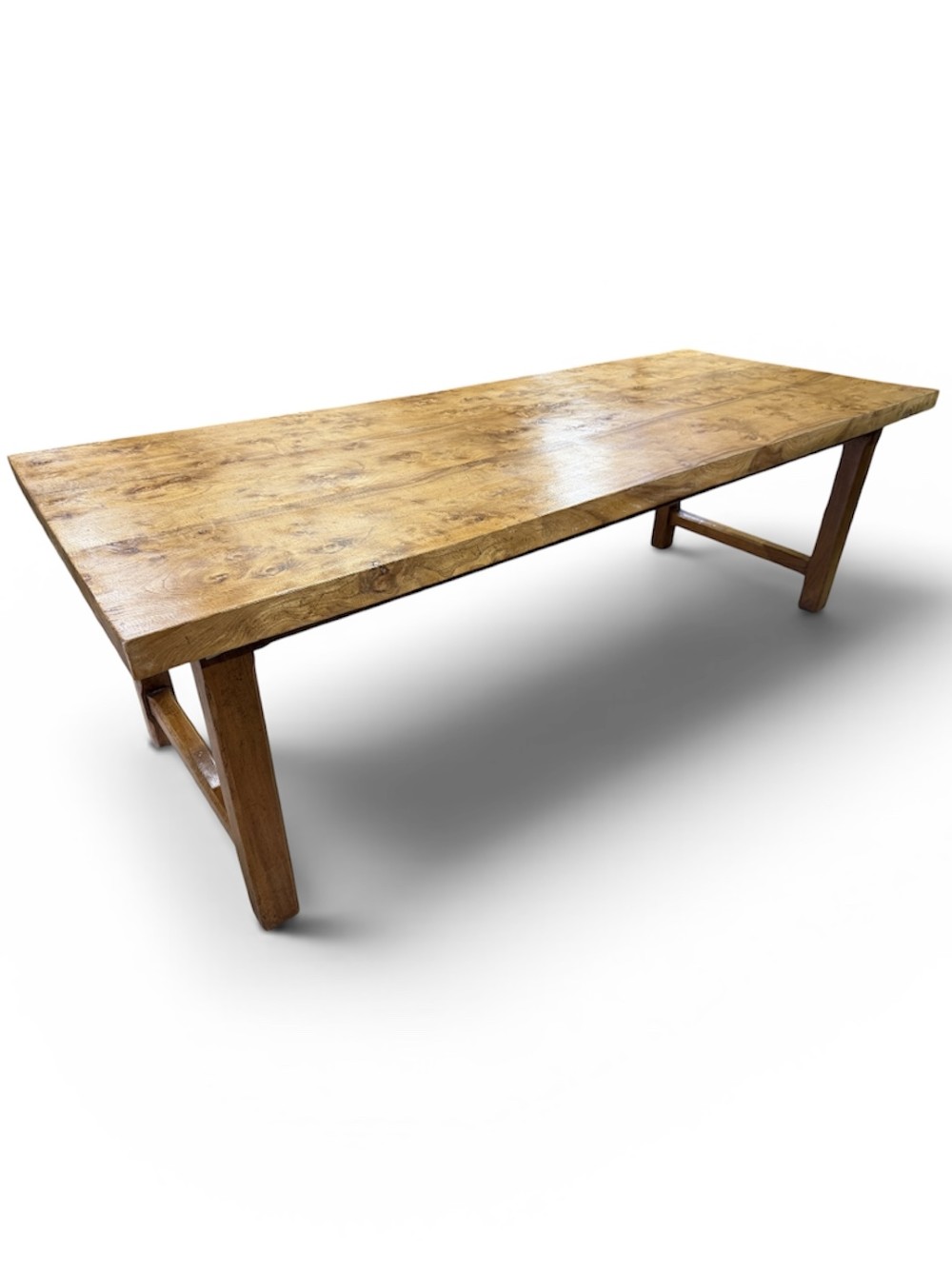 A long rectangular wooden farmhouse dining table featuring a plank top and sturdy trestle leg base in a warm honey oak finish.