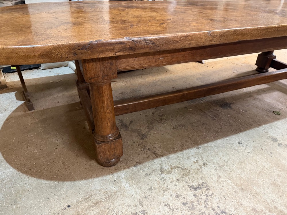 A long antique oak dining table featuring a thick single plank top with rounded ends supported by a low wooden stretcher base. View IV
