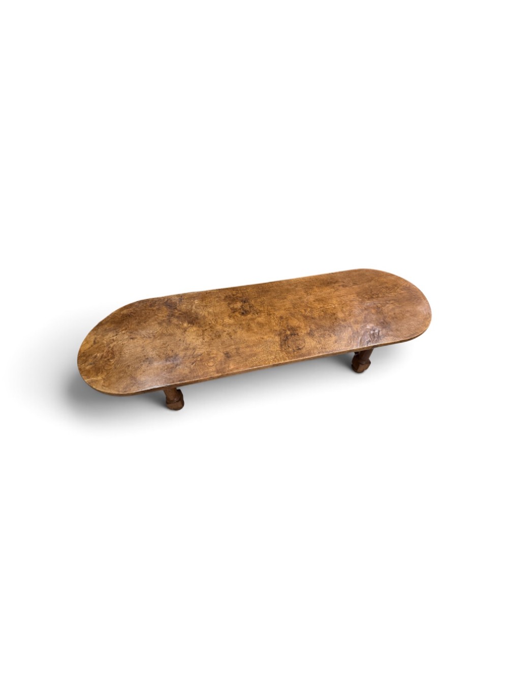 A long antique oak dining table featuring a thick single plank top with rounded ends supported by a low wooden stretcher base. View VII