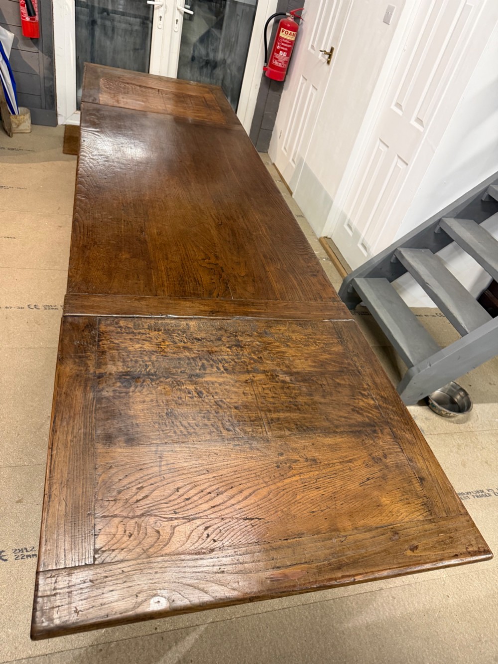 A long antique oak extending dining table featuring two end extension leaves, side frieze drawers, and tapered square legs. View II