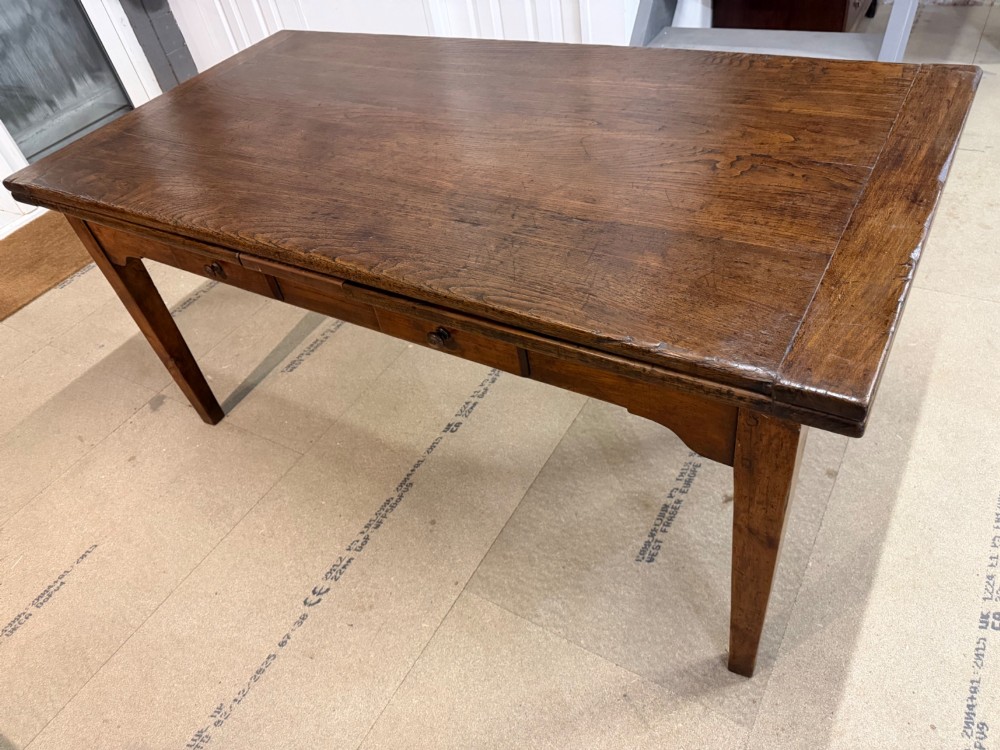 A long antique oak extending dining table featuring two end extension leaves, side frieze drawers, and tapered square legs. View VI
