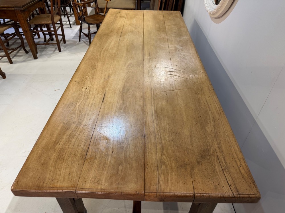 A 19th-century French beech farmhouse dining table with a light timber plank top and dark wooden frame supported by an H-stretcher. View IV