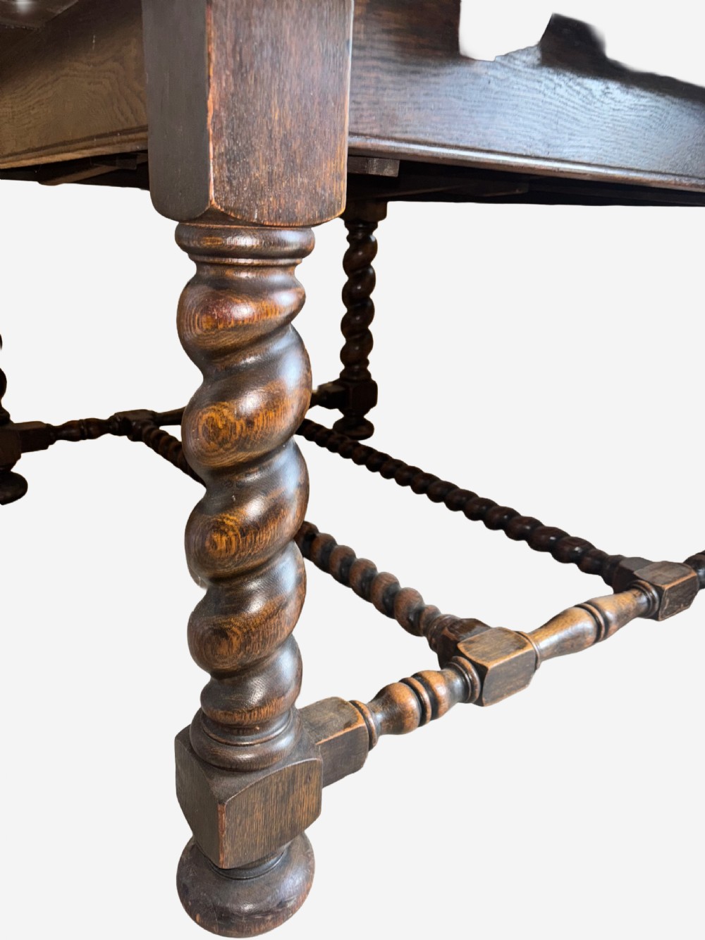 A dark oak draw-leaf dining table supported by four thick barley twist legs and low turned stretchers. View II