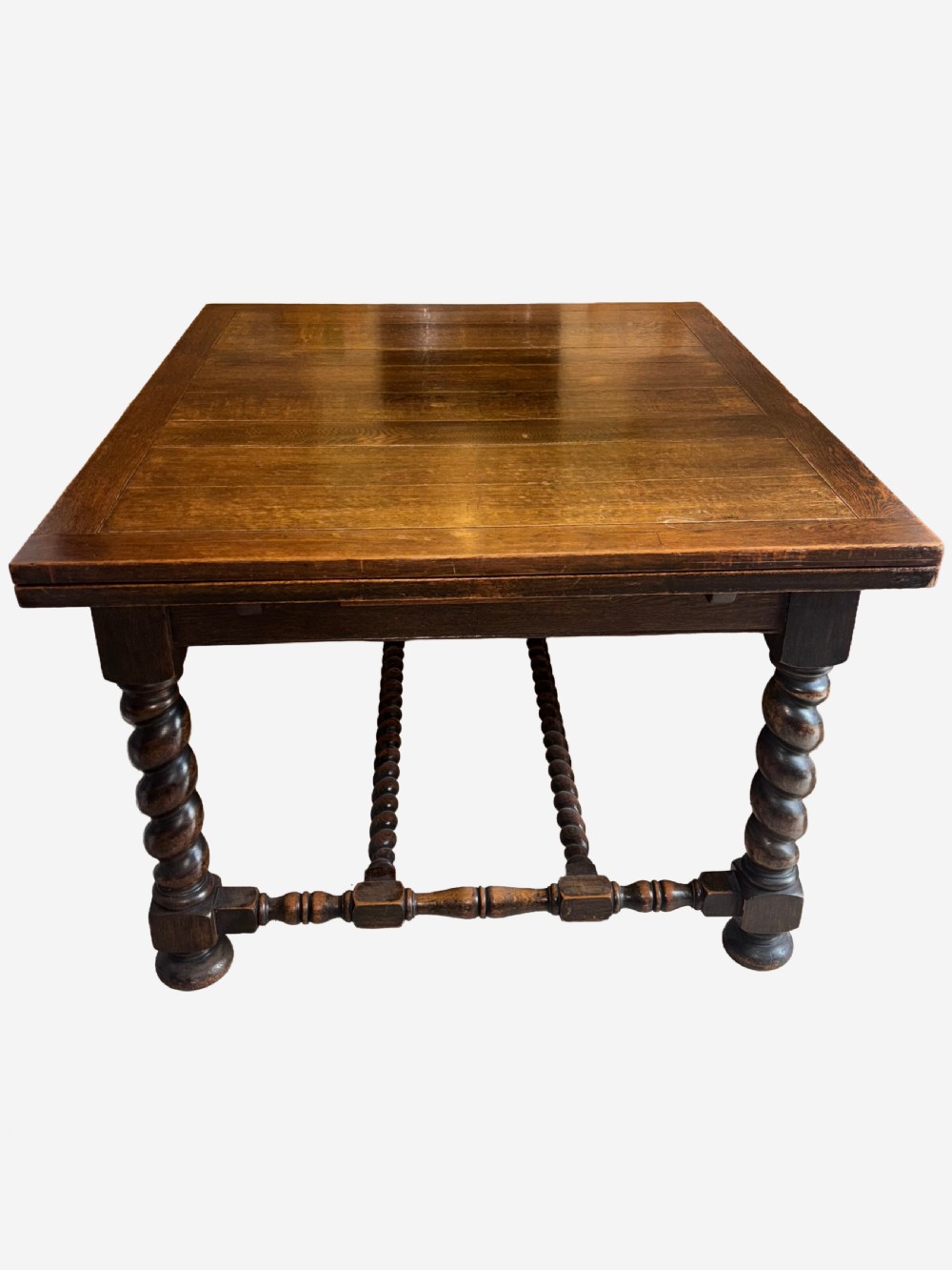 A dark oak draw-leaf dining table supported by four thick barley twist legs and low turned stretchers. View III