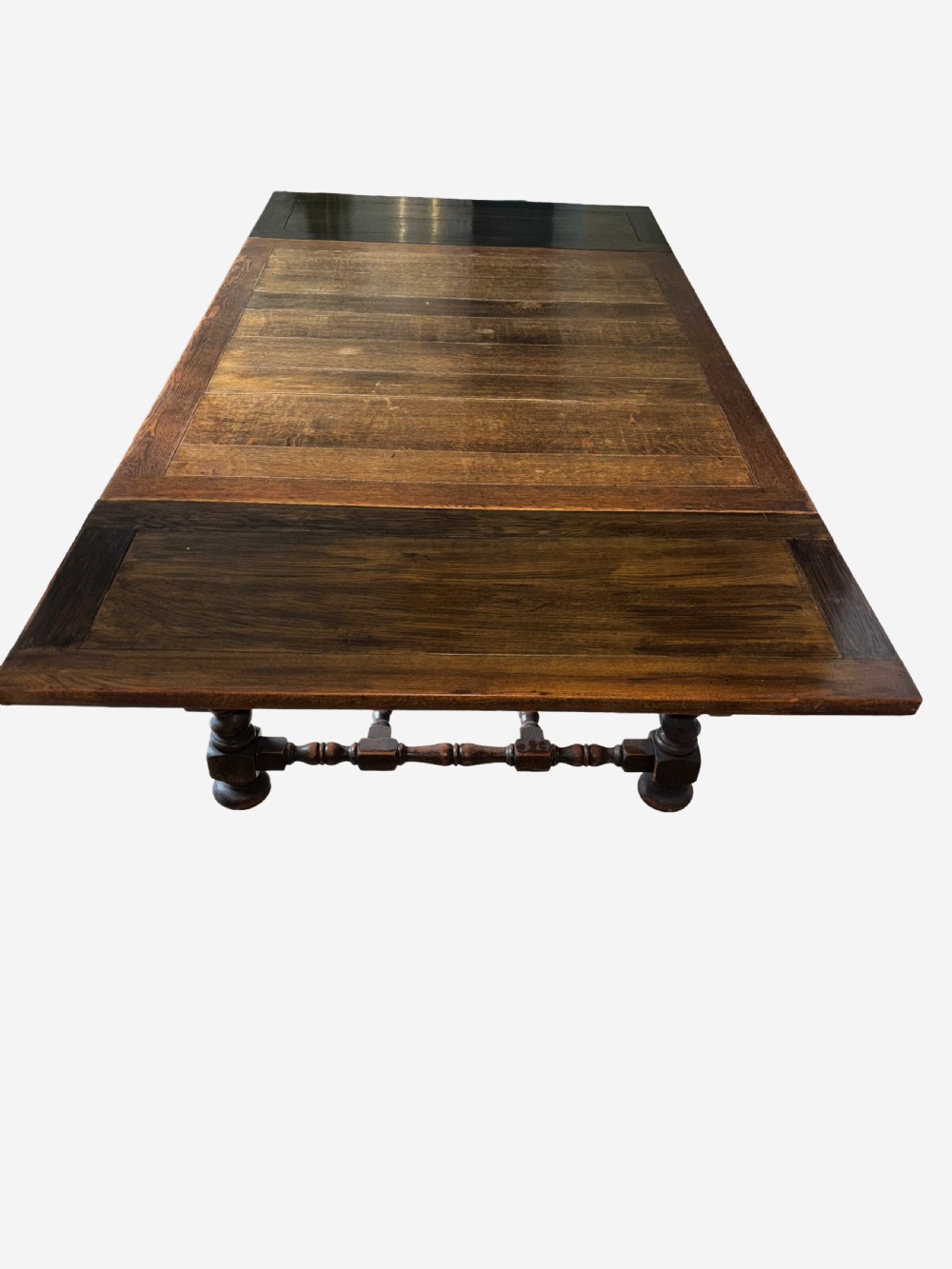 A dark oak draw-leaf dining table supported by four thick barley twist legs and low turned stretchers. View IV