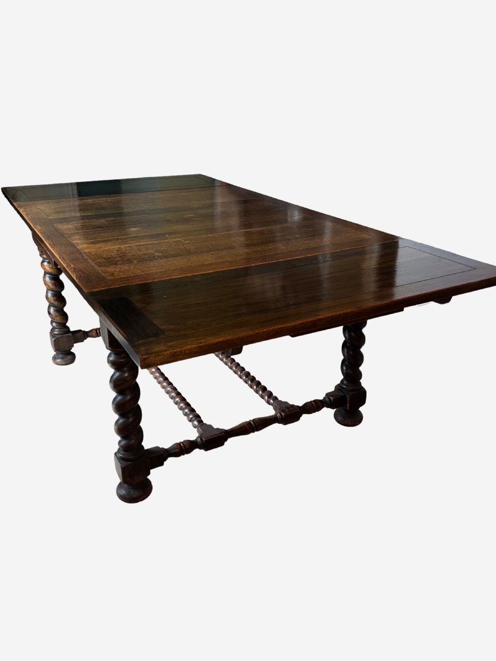 A dark oak draw-leaf dining table supported by four thick barley twist legs and low turned stretchers. View V