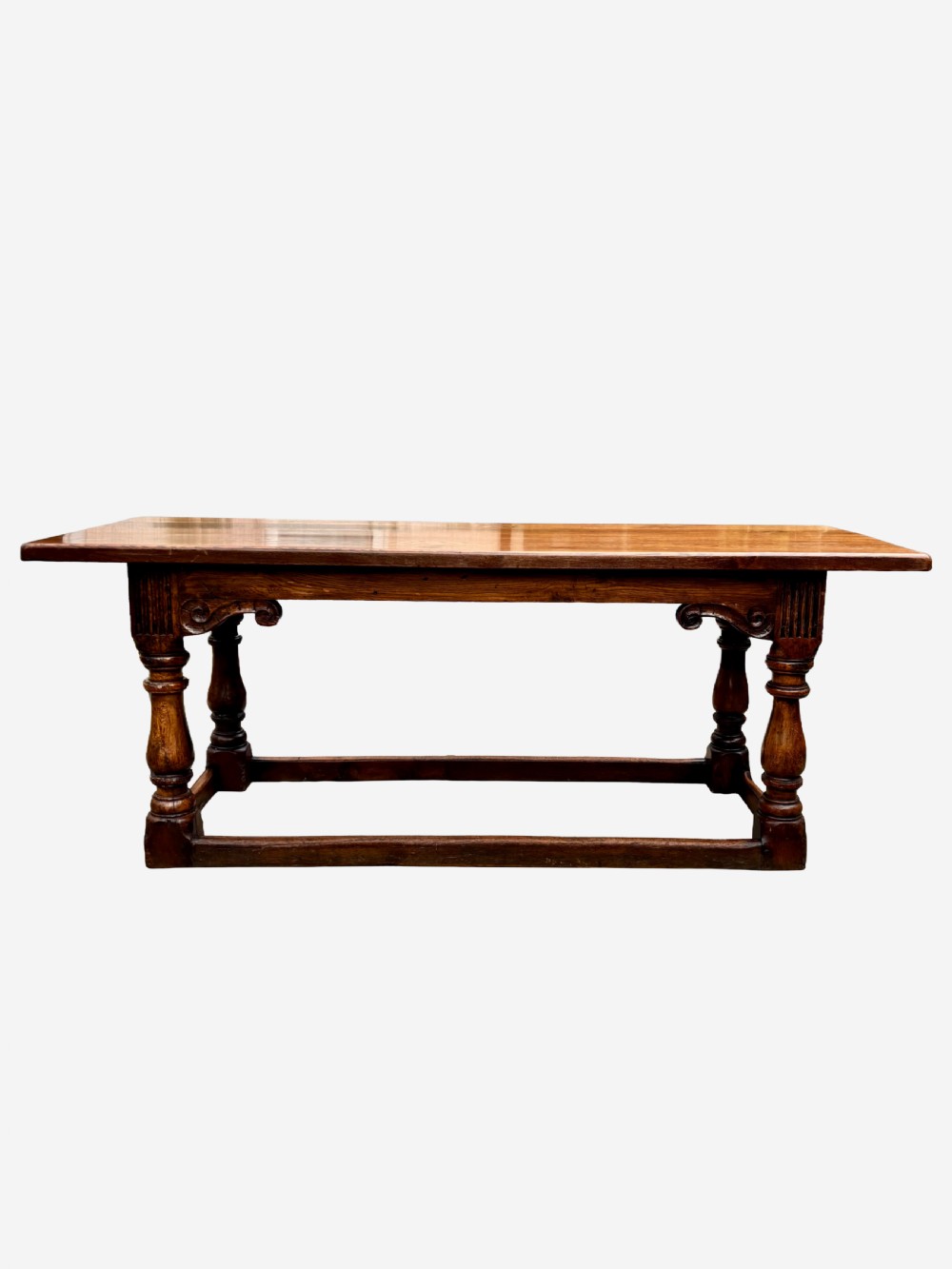 A mid-Victorian solid oak refectory table featuring turned baluster legs, a carved frieze, and a low perimeter stretcher. View II