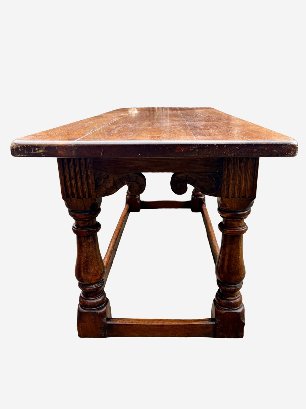 A mid-Victorian solid oak refectory table featuring turned baluster legs, a carved frieze, and a low perimeter stretcher. View III