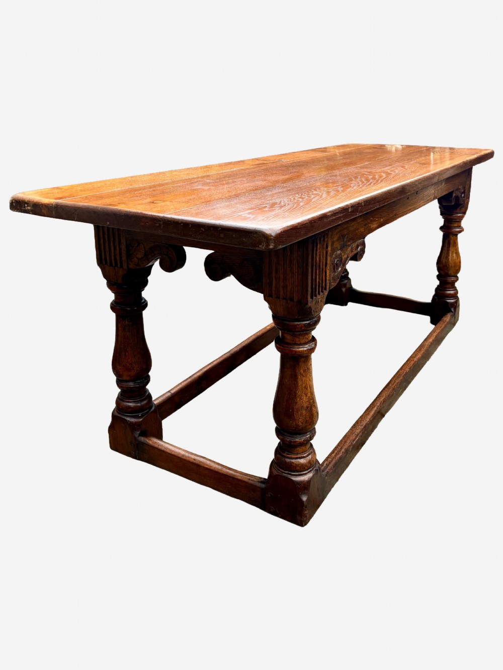 A mid-Victorian solid oak refectory table featuring turned baluster legs, a carved frieze, and a low perimeter stretcher. View V