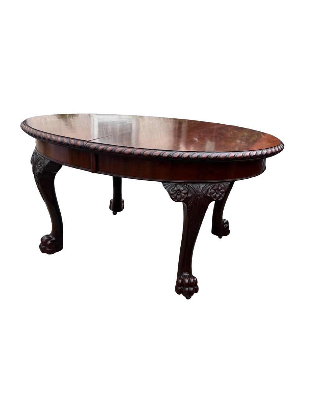 An oval mahogany Chippendale style extending dining table with carved cabriole legs, ball and claw feet, and a rope-twist carved apron rim.