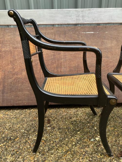 AN ANTIQUE PAIR OF EBONISED AND CANE ELBOW CHAIRSIN THE REGENCY STYLE - ADDITIONAL PHOTO 1