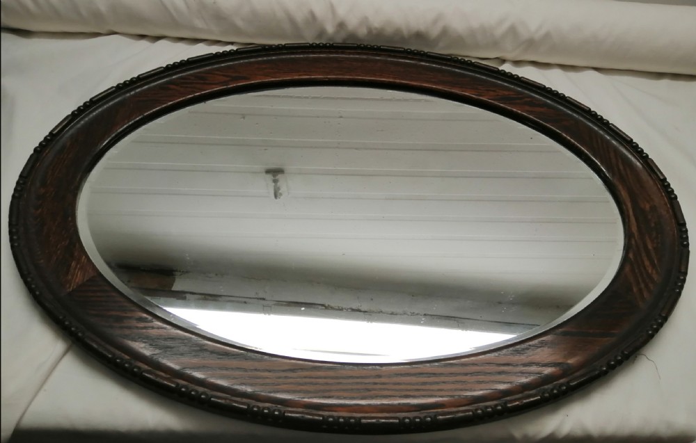 A large Edwardian oval oak mirror.