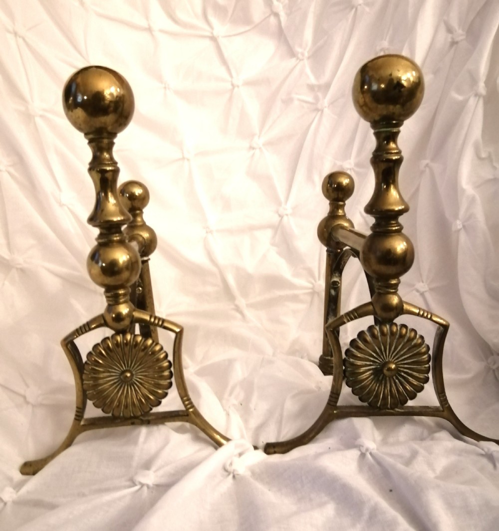 An antique pair of arts and crafts firedogs with sunflower decor.