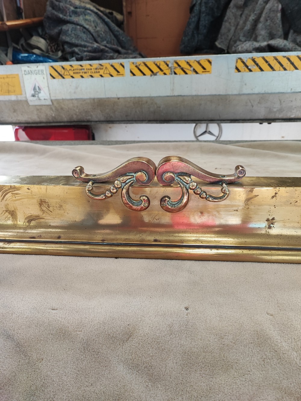 An elongated Victorian brass and copper fireplace fender featuring raised scrollwork mounts and decorative corner detailing. View II