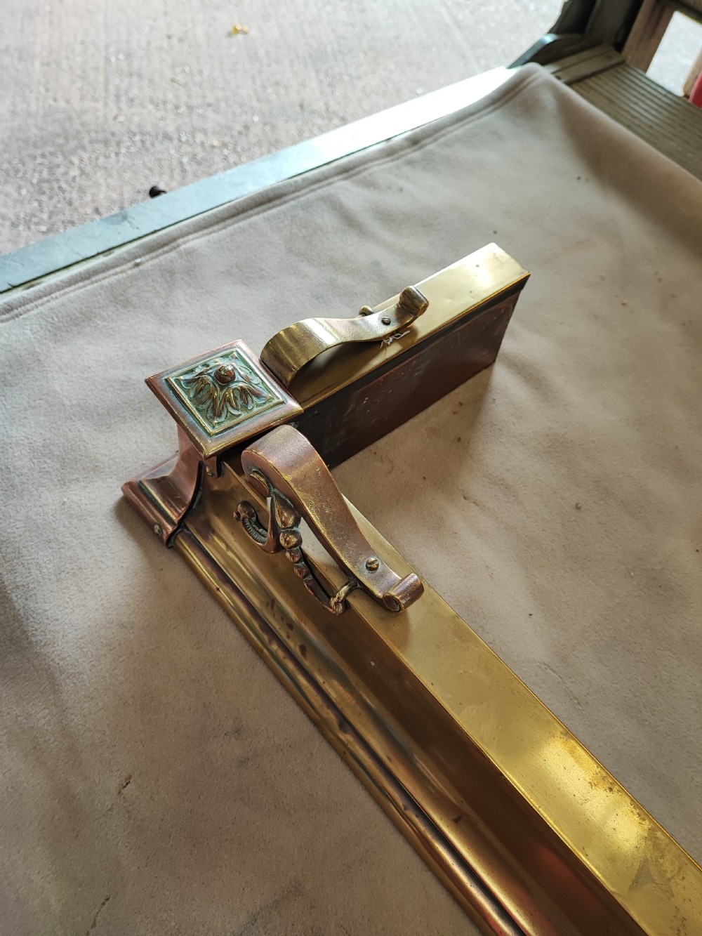 An elongated Victorian brass and copper fireplace fender featuring raised scrollwork mounts and decorative corner detailing. View IV