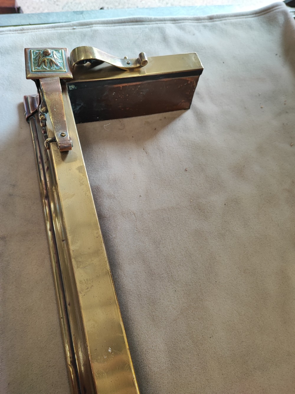 An elongated Victorian brass and copper fireplace fender featuring raised scrollwork mounts and decorative corner detailing. View V