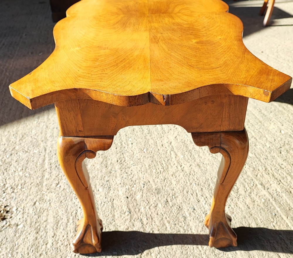 An antique walnut coffee table featuring a serpentine-shaped top with figured grain, supported by four cabriole legs ending in carved ball and claw feet. View II