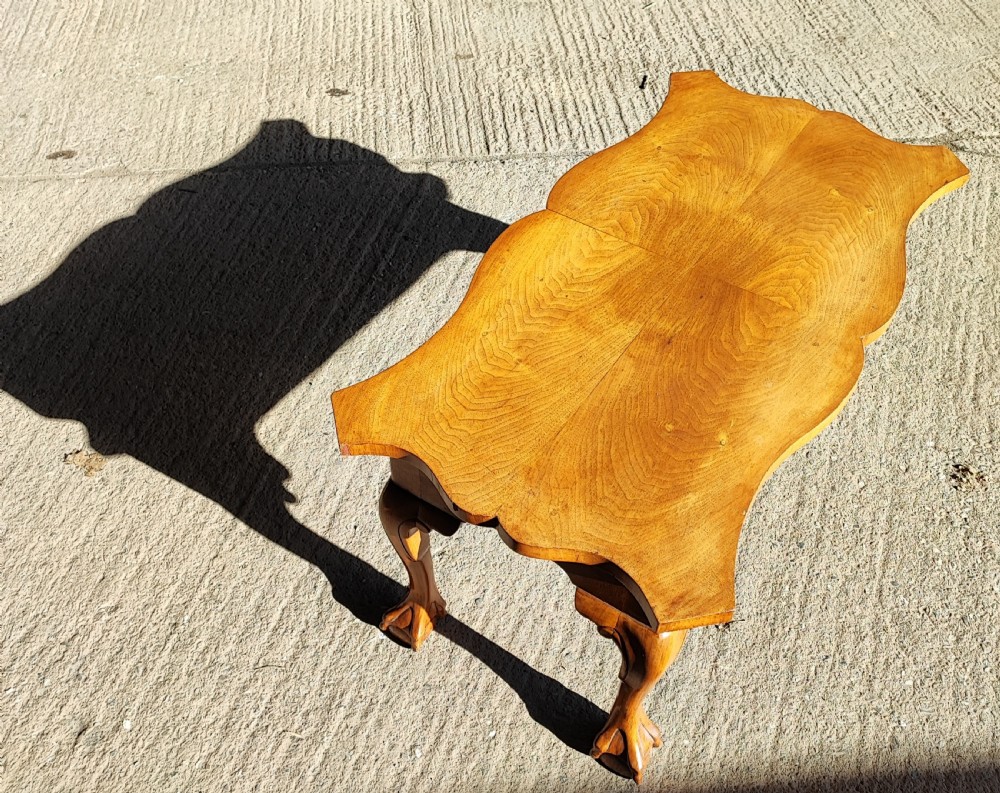 An antique walnut coffee table featuring a serpentine-shaped top with figured grain, supported by four cabriole legs ending in carved ball and claw feet. View III
