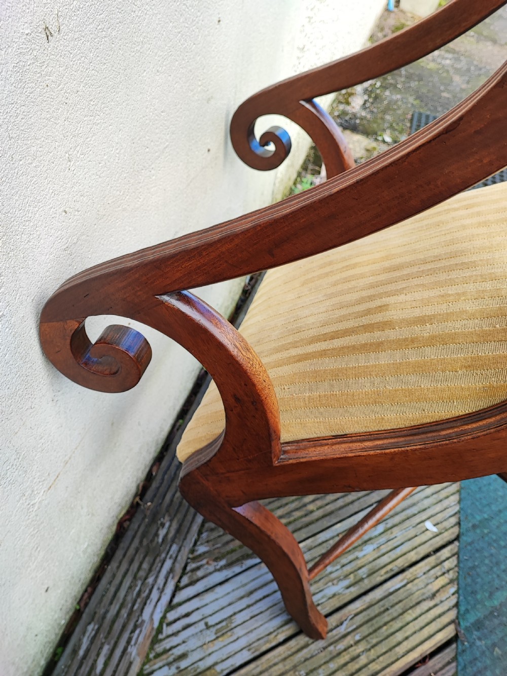 A Regency mahogany armchair featuring curved scroll arms, sabre legs, cross stretchers, and a yellow striped fabric seat. View II