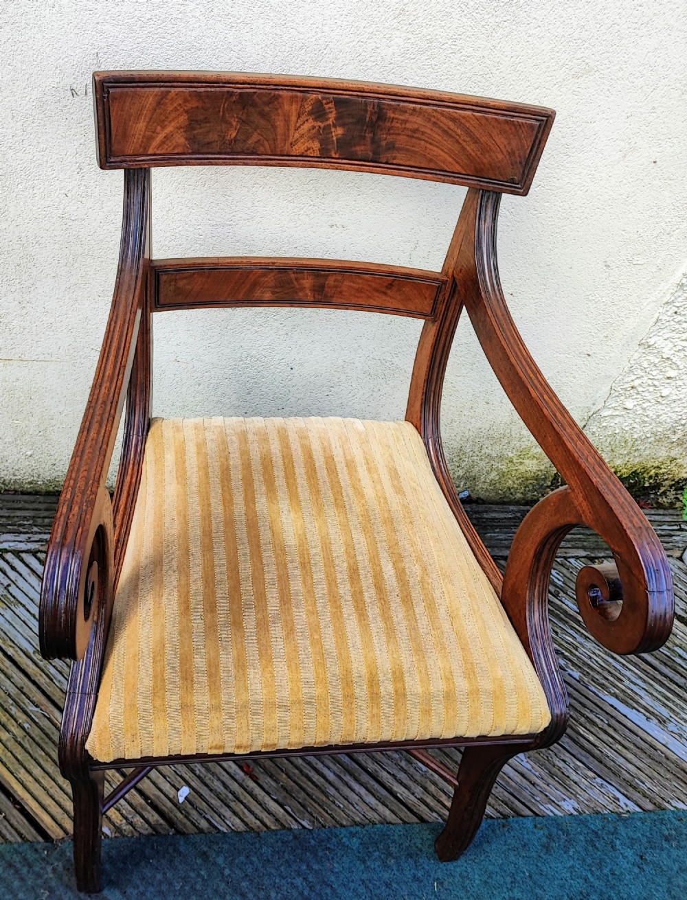 A Regency mahogany armchair featuring curved scroll arms, sabre legs, cross stretchers, and a yellow striped fabric seat. View X