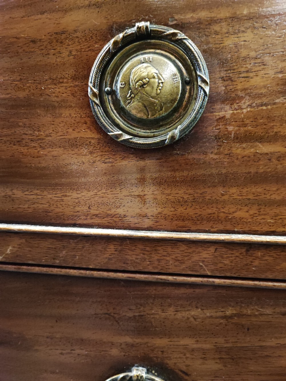 A rare Georgian mahogany chest of drawers,with original handles depicts the profile of King George III. View IX