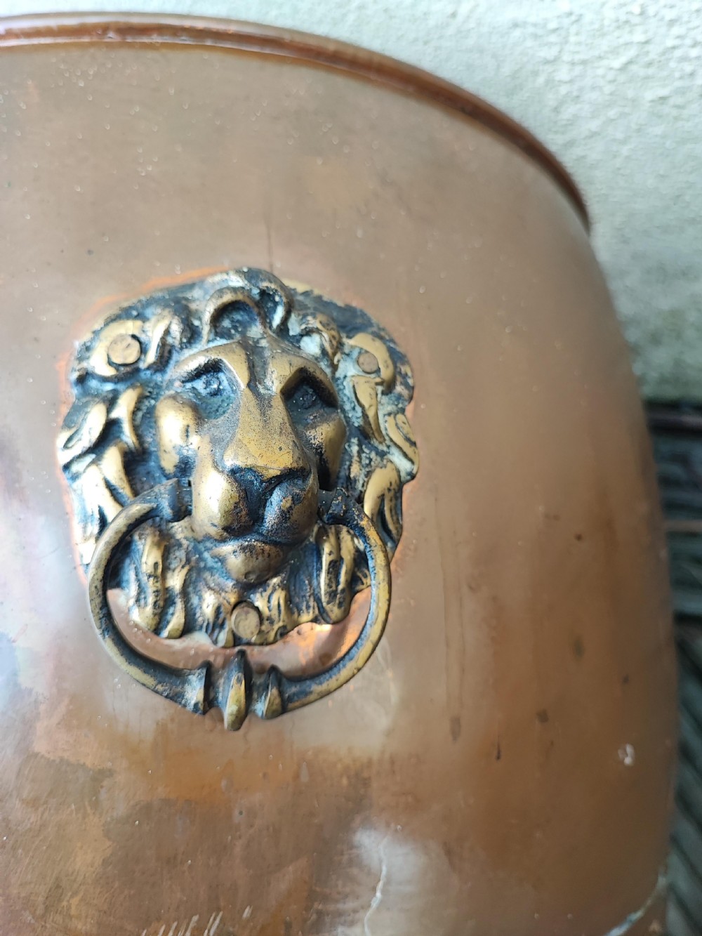 A deep cylindrical copper log bin featuring riveted side seams, brass lion-mask drop-ring handles, and raised paw feet. View VI