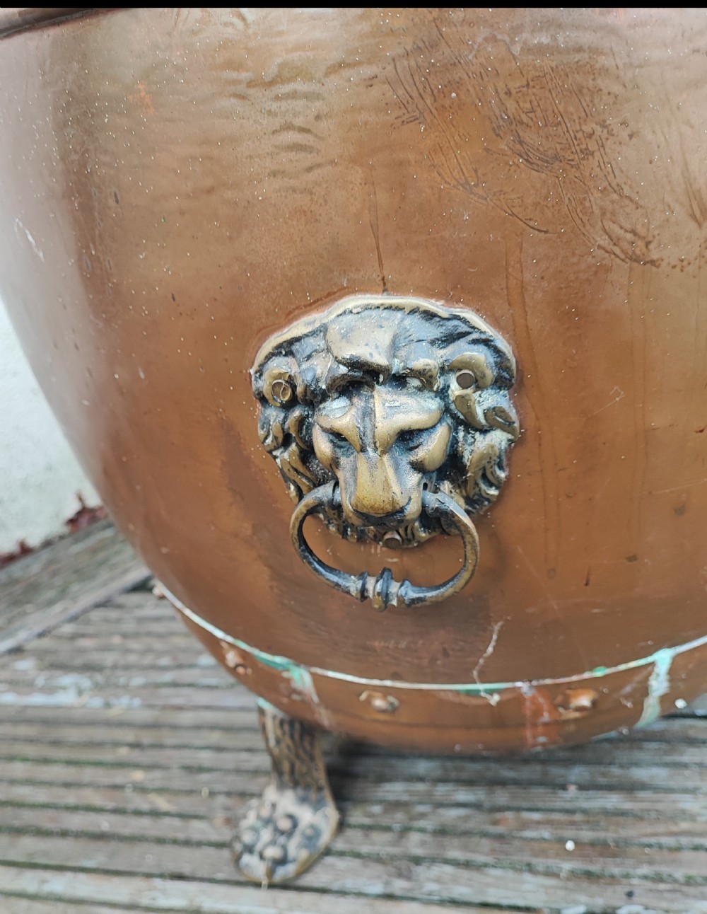 A deep cylindrical copper log bin featuring riveted side seams, brass lion-mask drop-ring handles, and raised paw feet. View VII