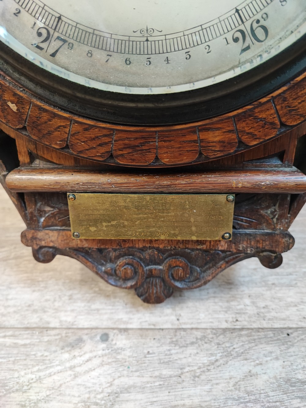 A carved oak wall barometer featuring an upper thermometer flanked by turned columns above a circular aneroid dial. View VI