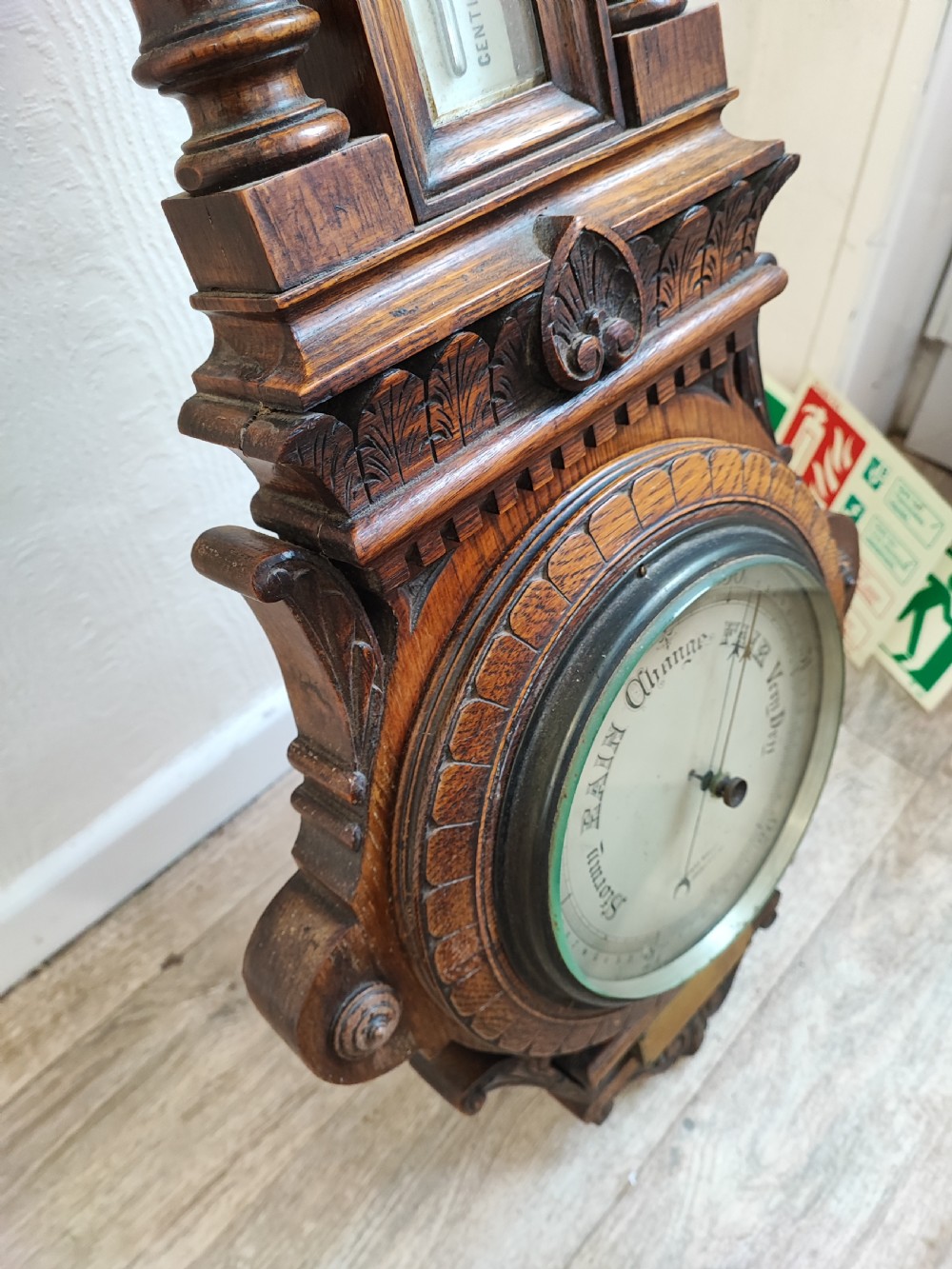 A carved oak wall barometer featuring an upper thermometer flanked by turned columns above a circular aneroid dial. View VIII