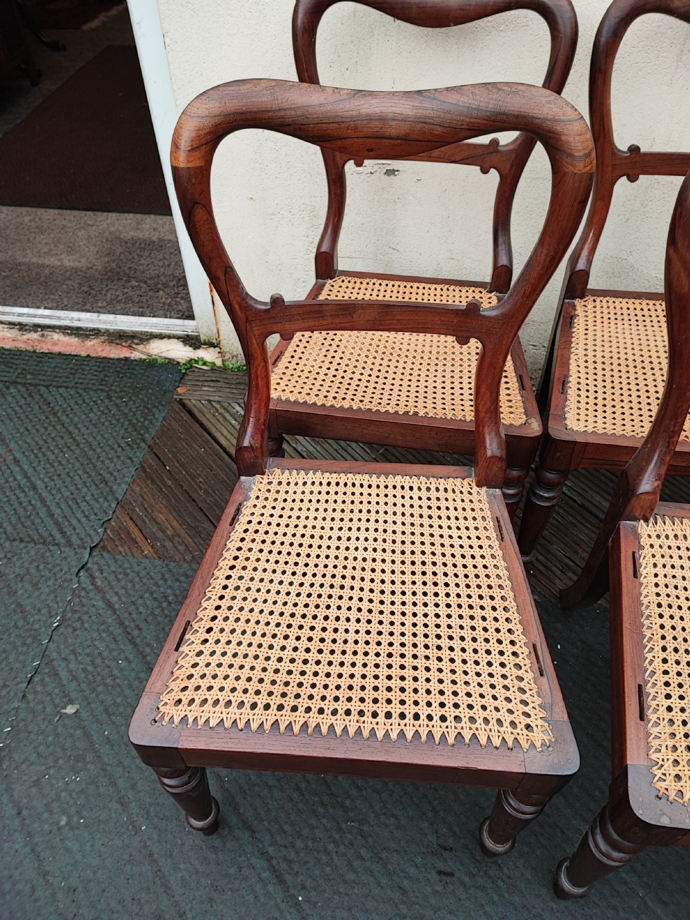 A set of six Regency rosewood dining chairs featuring swept open backrests, turned front legs, and woven natural cane seats. View II