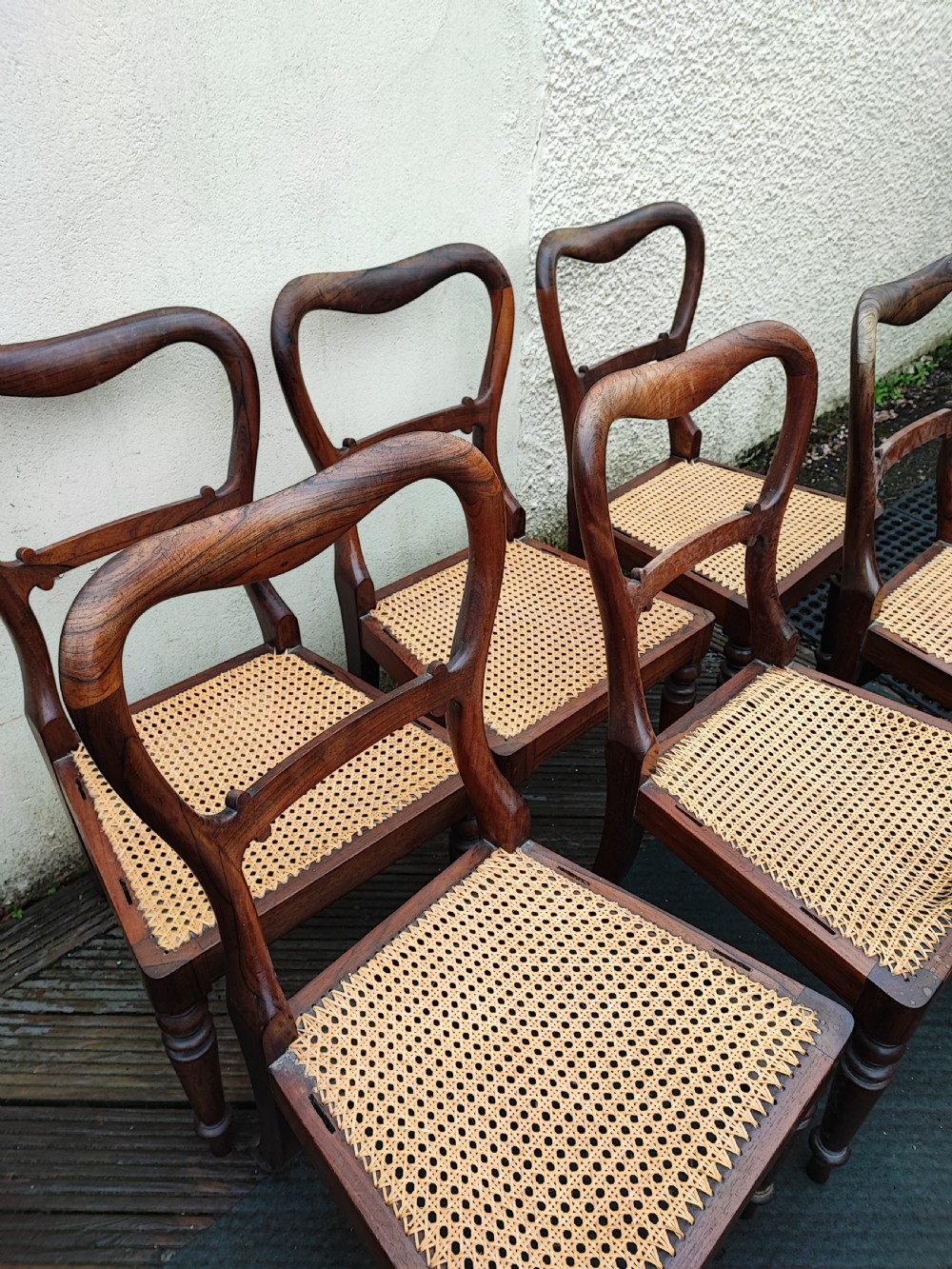 A set of six Regency rosewood dining chairs featuring swept open backrests, turned front legs, and woven natural cane seats. View III
