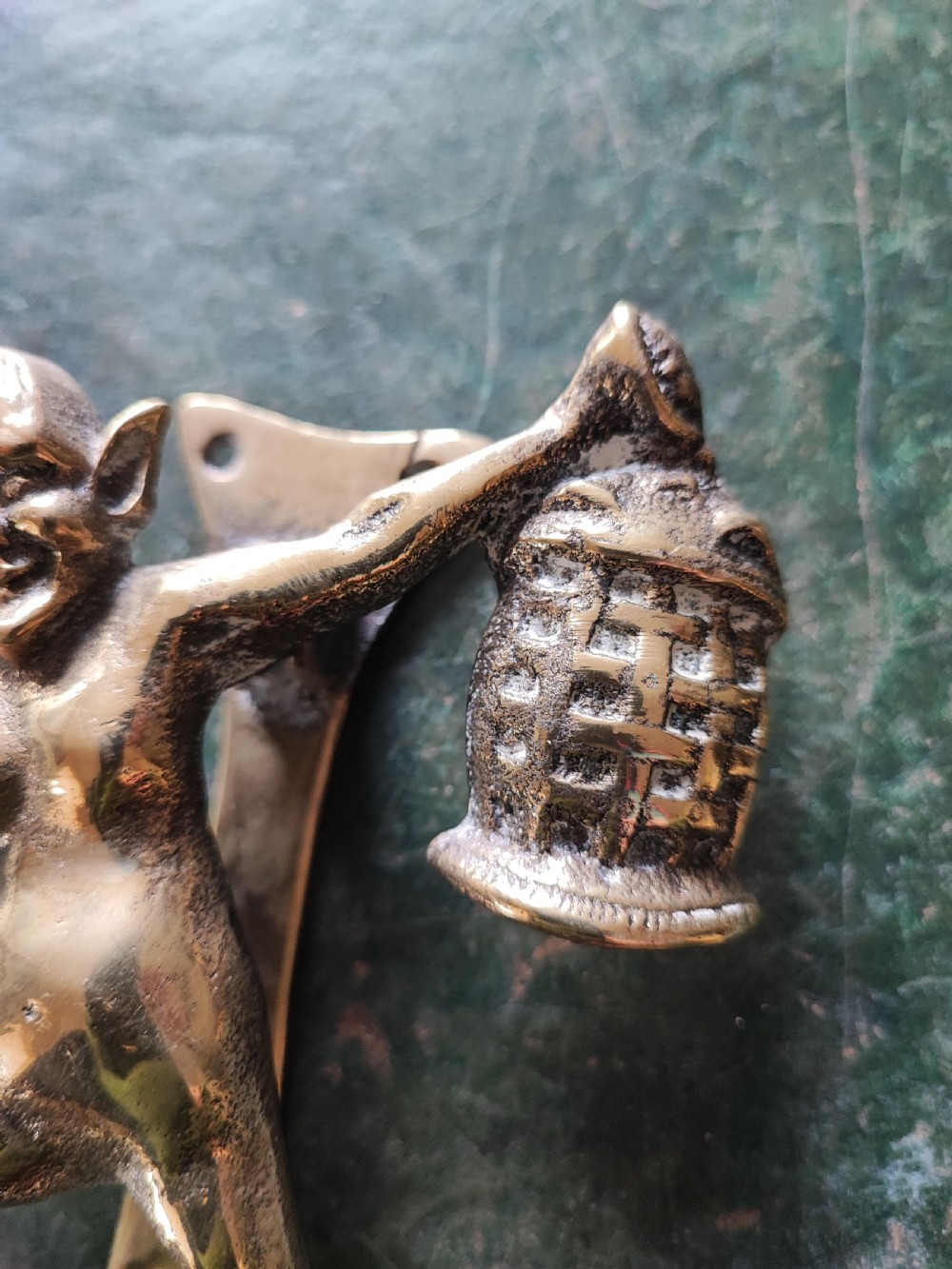 An antique solid brass door knocker sculpted in the shape of a whimsical imp holding a lantern while standing atop a mushroom base. View II