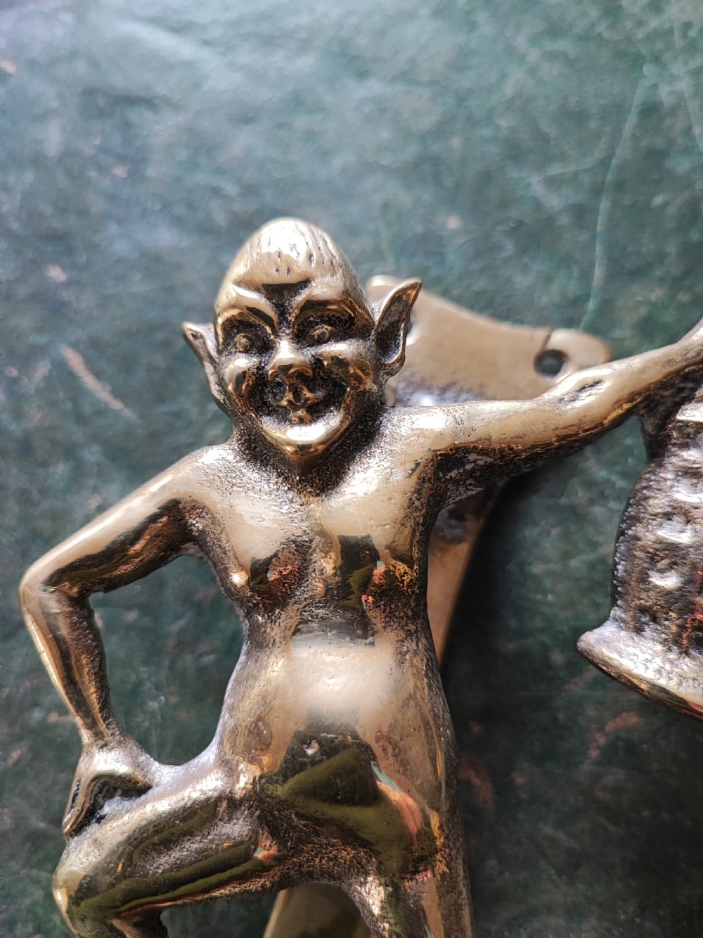 An antique solid brass door knocker sculpted in the shape of a whimsical imp holding a lantern while standing atop a mushroom base. View VI