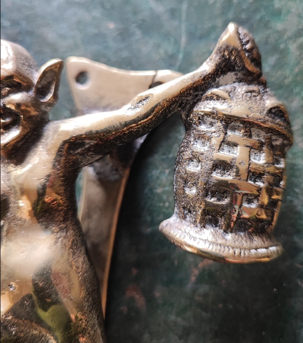 An antique solid brass door knocker sculpted in the shape of a whimsical imp holding a lantern while standing atop a mushroom base. View XII