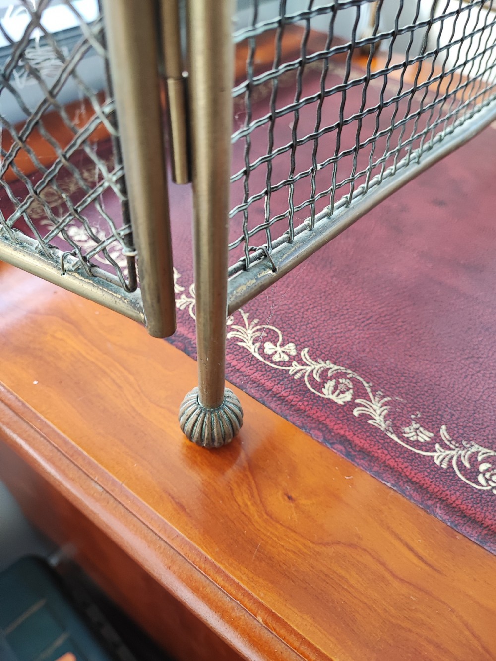 A Victorian brass spark guard featuring a central woven mesh panel with an arched handle, flanked by two hinged side wings on ball feet. View II