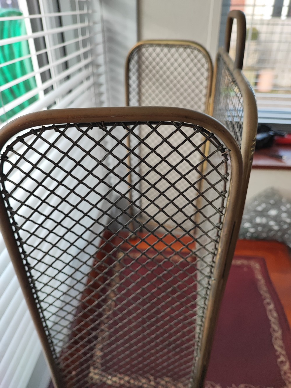 A Victorian brass spark guard featuring a central woven mesh panel with an arched handle, flanked by two hinged side wings on ball feet. View IV