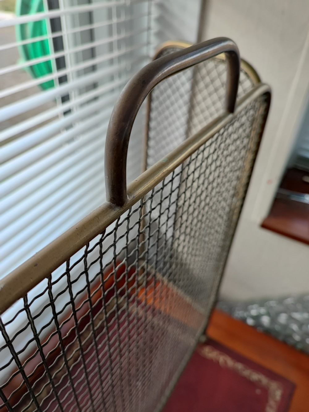 A Victorian brass spark guard featuring a central woven mesh panel with an arched handle, flanked by two hinged side wings on ball feet. View VI