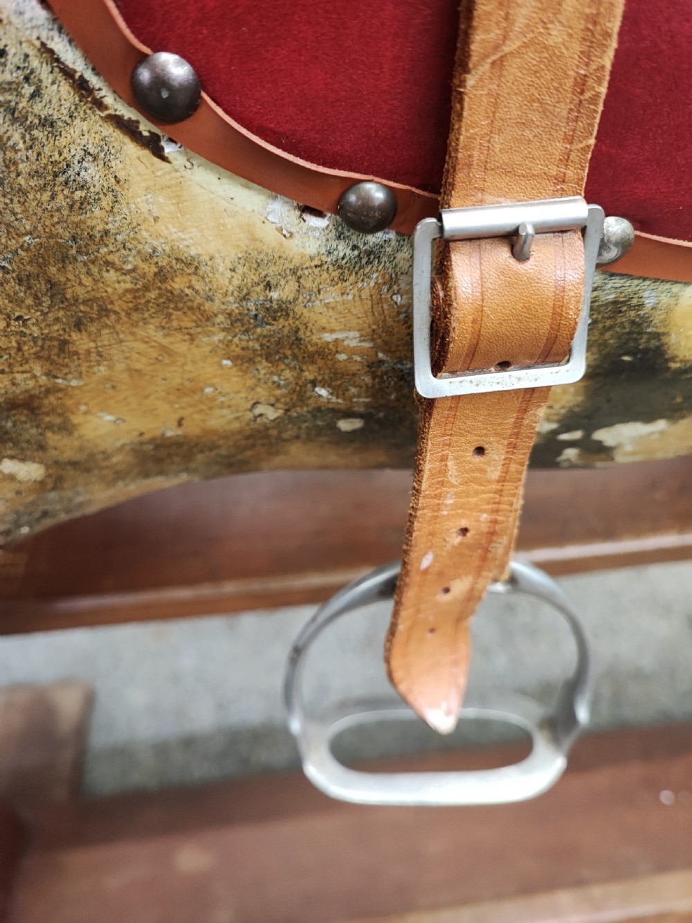 A large antique carved wooden rocking horse with a dappled painted finish, leather saddle, horsehair mane, and tail, mounted on a wooden safety stand. View VII