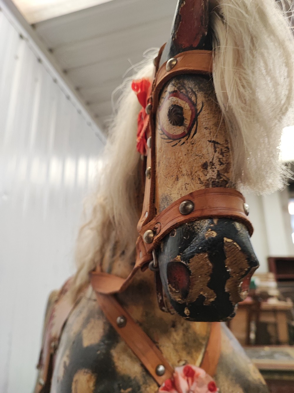 A large antique carved wooden rocking horse with a dappled painted finish, leather saddle, horsehair mane, and tail, mounted on a wooden safety stand. View IX