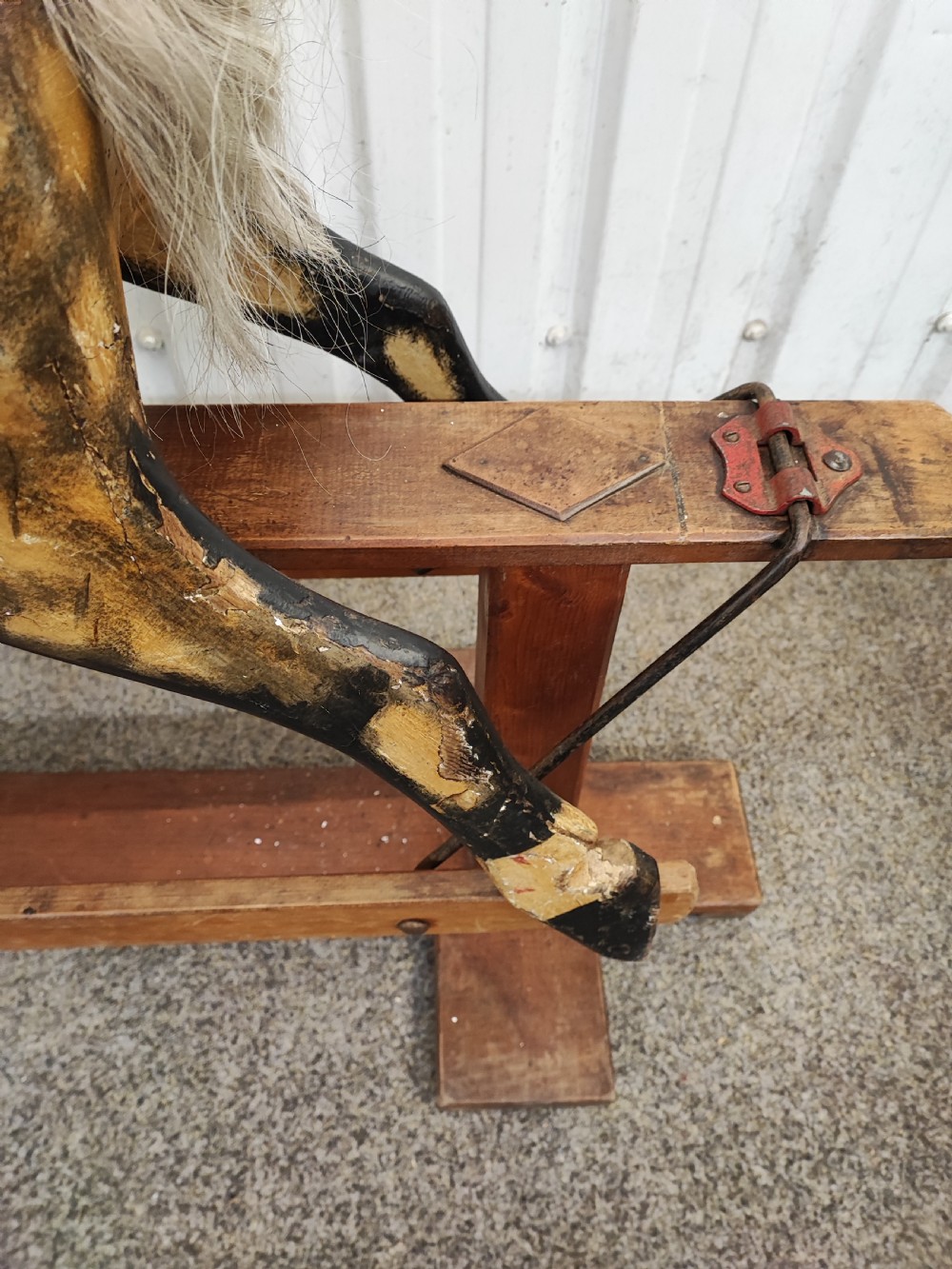 A large antique carved wooden rocking horse with a dappled painted finish, leather saddle, horsehair mane, and tail, mounted on a wooden safety stand. View X