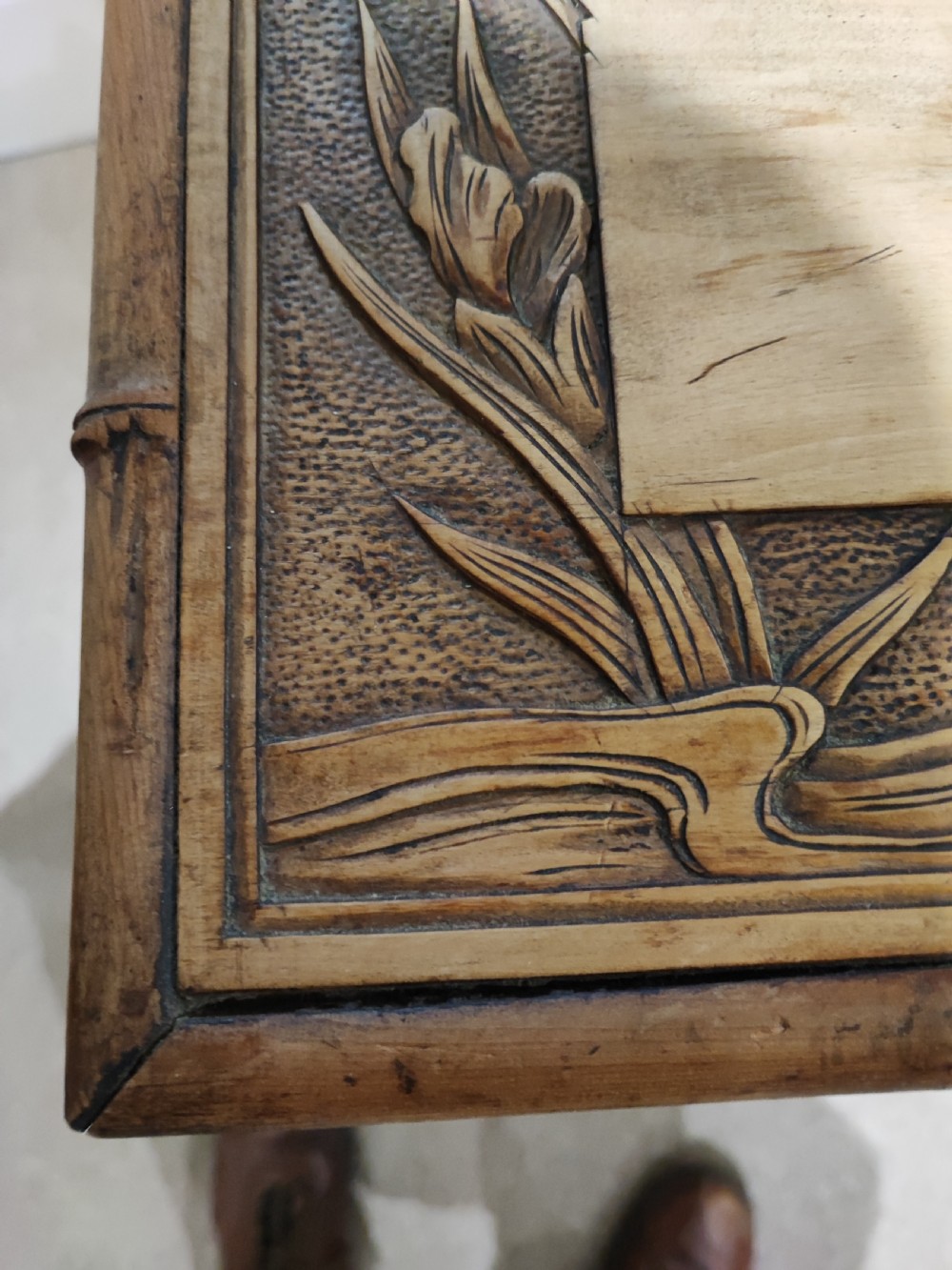 A square Arts and Crafts wooden side table featuring carved iris botanical motifs, bamboo-style edge moulding, shaped legs, and a carved lower shelf. View VI