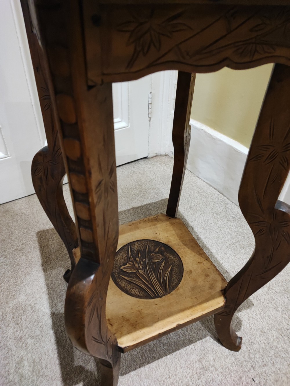 A square Arts and Crafts wooden side table featuring carved iris botanical motifs, bamboo-style edge moulding, shaped legs, and a carved lower shelf. View VIII