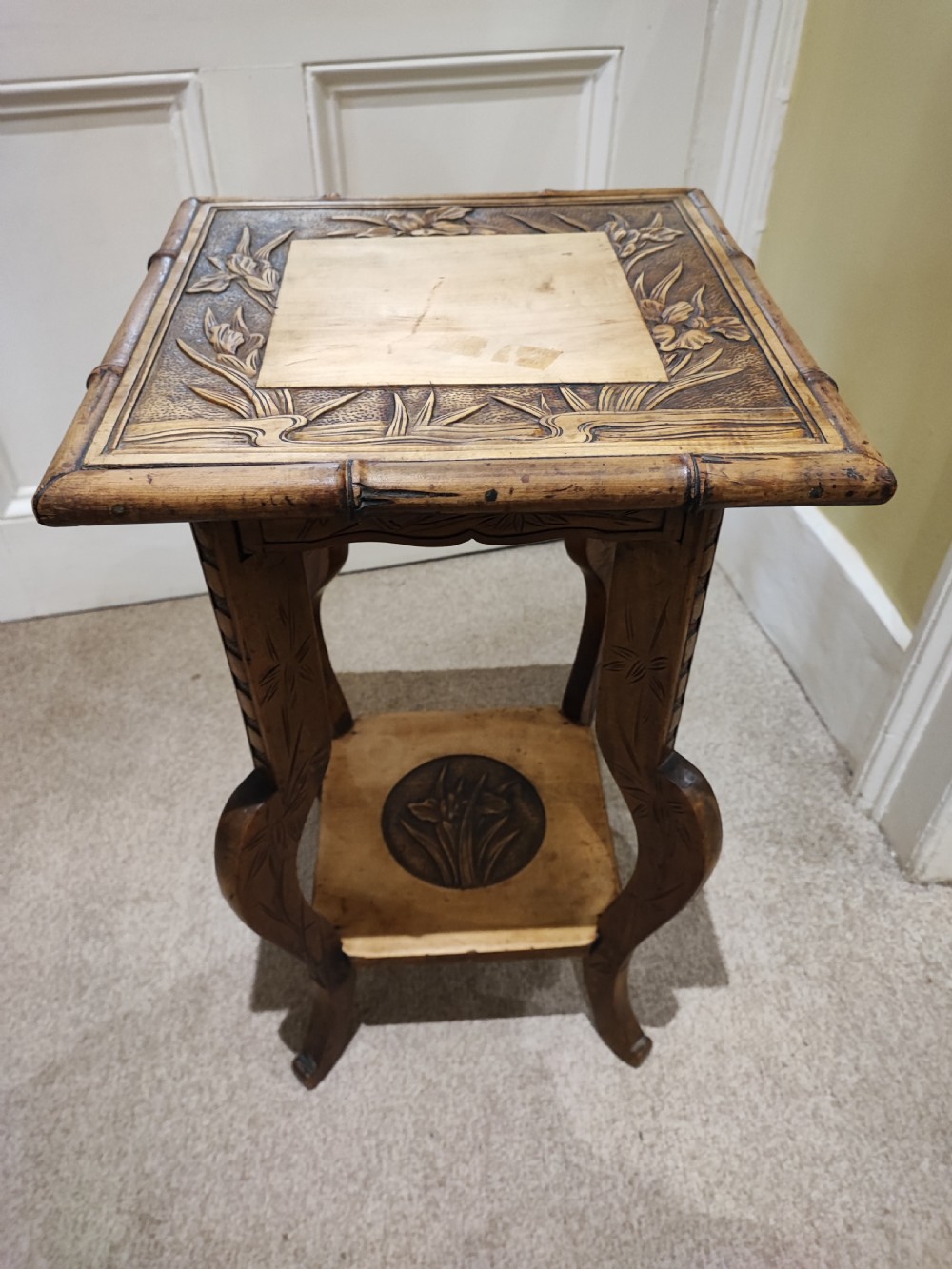 A square Arts and Crafts wooden side table featuring carved iris botanical motifs, bamboo-style edge moulding, shaped legs, and a carved lower shelf. View IX