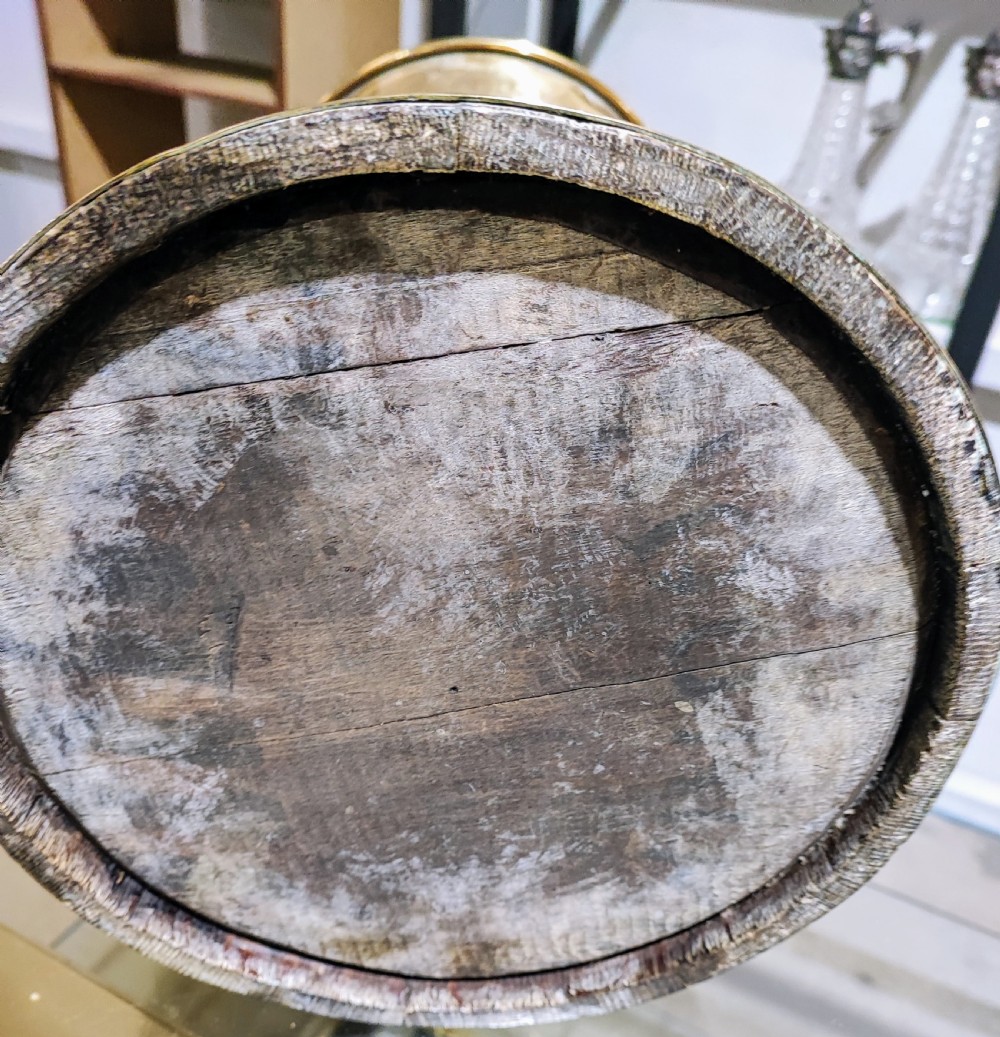 An antique coopered oak stick stand bound with polished riveted brass bands and topped with a flared brass collar. View II